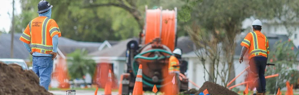 Vacuum excavation rig and conduit reel staged in a neighborhood